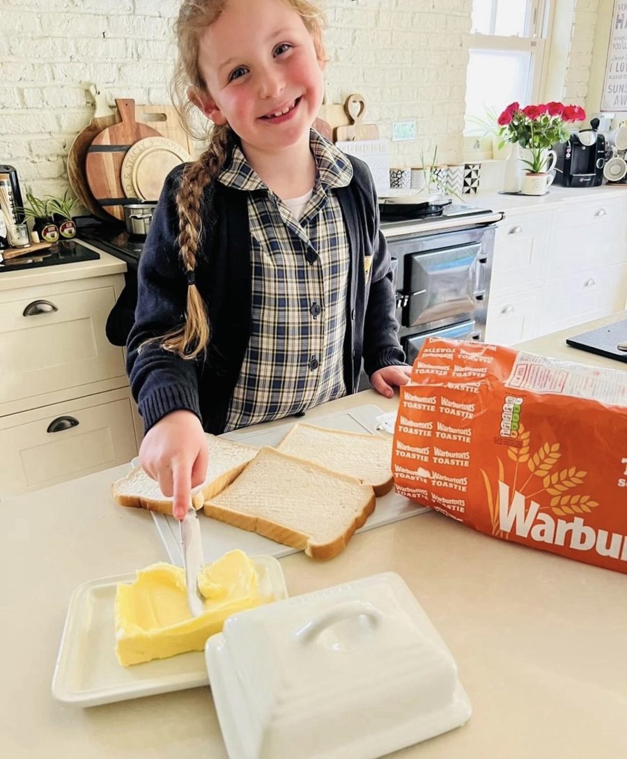 Elsie in her school uniform buttering bread next to a loaf